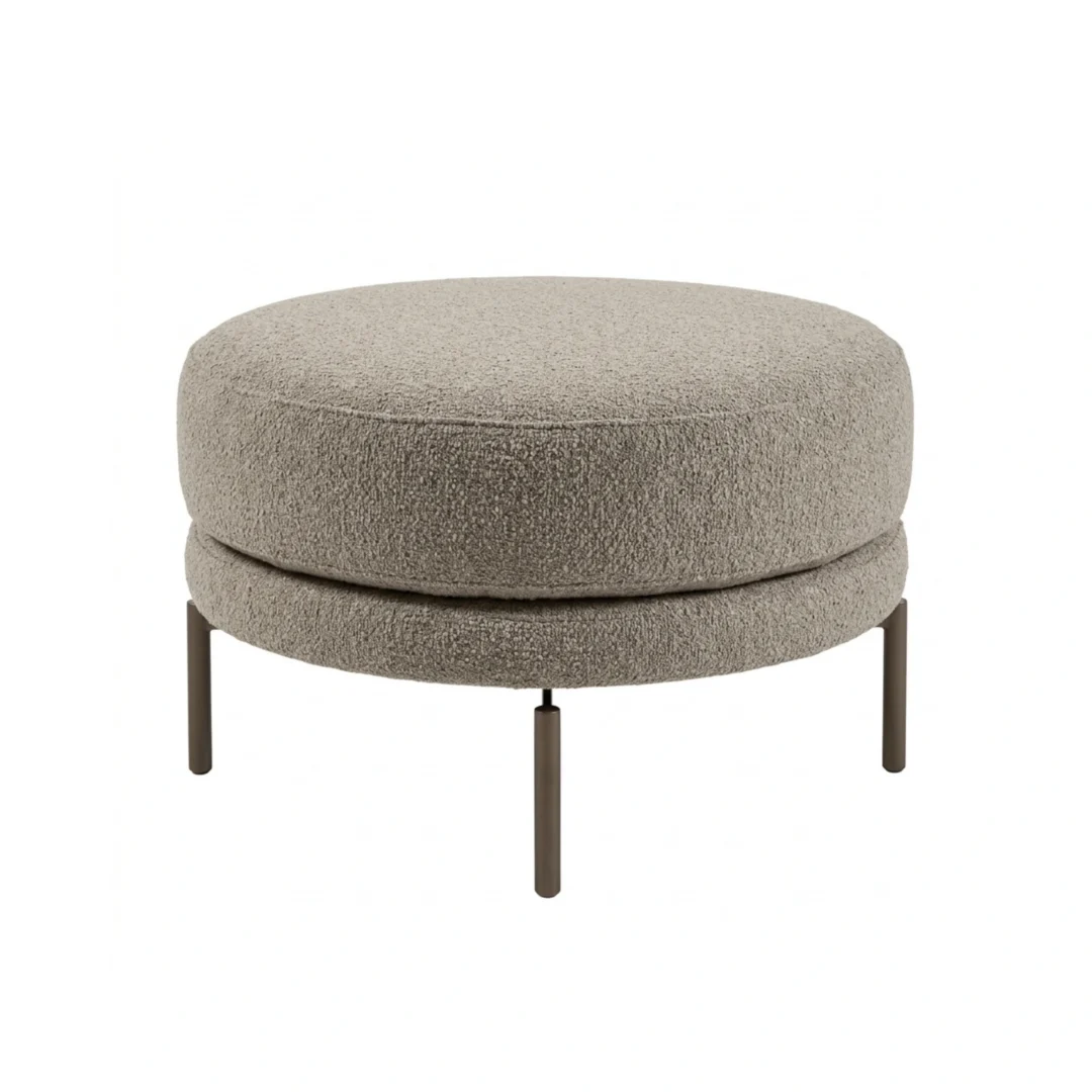 Round ottoman with fabric-like upholstery and four straight cylindrical legs, shown from a front angle.